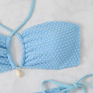 Detail of sky blue bikini top with popcorn texture fabric and small white shell pendant