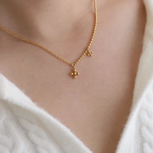 Minimalist 18K gold-plated beaded cross chain necklace worn over a white sweater
