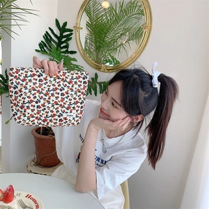 Détail d'une trousse de maquillage en velours côtelé à fleurs avec étiquette de marque