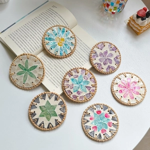 Macro shot of circular rattan coasters with colorful seashell mosaic floral patterns