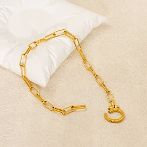 Elegant gold titanium paperclip necklace with OT toggle clasp on a soft jewelry pillow