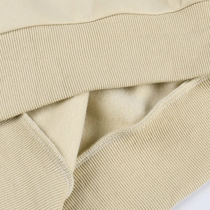 Détail rapproché des poignets côtelés et de la doublure polaire douce d'un sweat beige