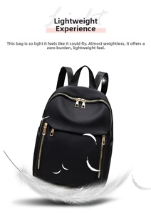 Detail of lightweight black nylon backpack with gold zippers and floating feathers