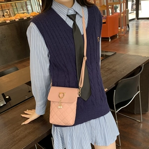 Pink quilted crossbody bag with golden cat ear clasp and pearl pendant on a model
