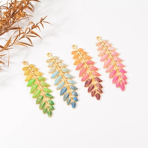 Detailed close-up of leaf-shaped jewelry pendants with vibrant colorful enamel gradients