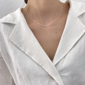 Close-up of minimalist 925 sterling silver twisted chain necklace on female model