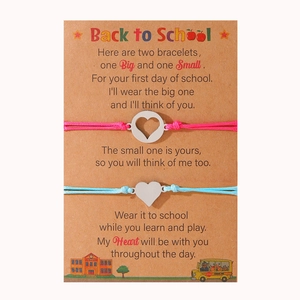 Dettaglio di braccialetti a cuore intrecciati rosa e blu su un biglietto regalo