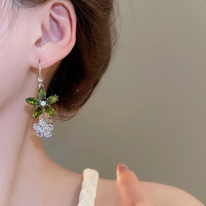 Vue détaillée d'une boucle d'oreille fleur en zircon avec pierres vertes et blanches