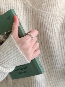 Detail of irregular silver minimalist ring worn with a dark green book background
