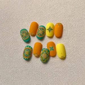 Makro-Detail von matten Böhmen-Nagelstickern mit orange-grünen Mandala-Blumenmustern