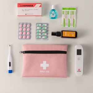 Pink portable first aid storage bag with white cross and medical supplies on grey background