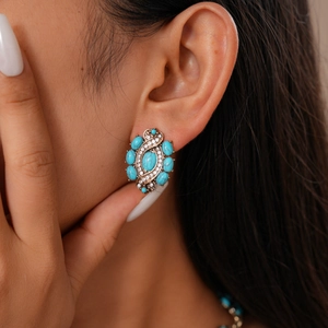 Gros plan de boucles d'oreilles vintage en résine turquoise et strass portées
