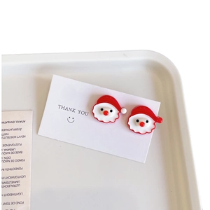 Boucles d'oreilles Père Noël mignonnes en émail rouge et blanc sur une carte cadeau blanche