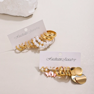 Detail of gold earring set with pearls and pink butterfly accents on display card