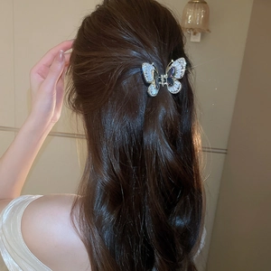 Vista macro di un fermaglio per capelli a farfalla in argento con zirconi blu su modella