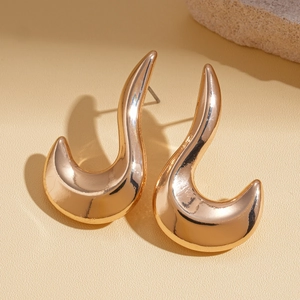 Macro shot of minimalist gold geometric curved stud earrings with polished metallic finish