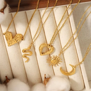 Set of five gold titanium steel necklaces with sun, moon, and heart pendants on beige cloth