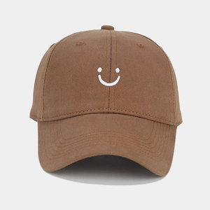 Detail of white smiley face embroidery on brown cotton twill baseball cap fabric