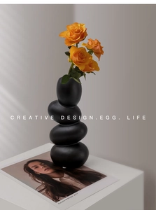Detail of matte black pebble ceramic vase with a creative stacked aesthetic and textured finish