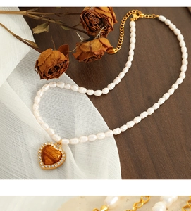 Dettaglio della collana di perle con ciondolo a cuore su legno vintage e tessuto