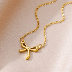 Close-up of gold 18k bow pendant necklace on elegant champagne silk background