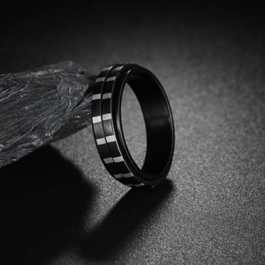 Close-up of black rotatable spinner ring with silver block patterns on dark stone