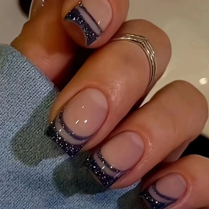Close-up of French short square press-on nails with navy blue glitter and wavy patterns