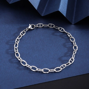 Macro shot of a silver mariner link bracelet with lobster clasp on blue textured paper