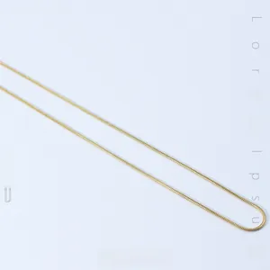 Detail of a minimalist gold-plated snake chain necklace with a smooth metallic texture