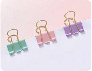 Close-up of three mint, pink, and purple hollow metal binder clips on white paper