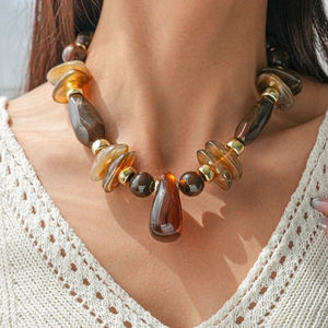 Détail d'un collier vintage en perles d'acrylique ambrées avec accents dorés