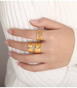 Close-up of three gold-plated titanium steel rings featuring chain, braided, and smooth textures