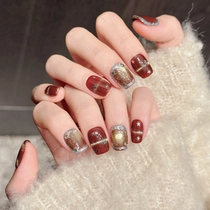 Handmade red glitter press-on nails with golden star patterns and cat eye finish