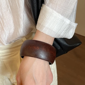 Detail of wide resin bangle featuring deep brown wood-like grain and smooth finish