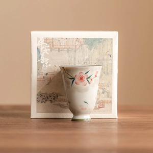 Hand-painted peach blossom ceramic teacup with elegant oriental gift box on wooden table
