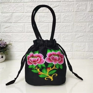 Close-up of colorful floral embroidery and drawstring closure on black ethnic bucket bag