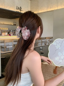 Dettaglio della pinza per capelli con fiore in rete rosa sfumata indossata su capelli lunghi