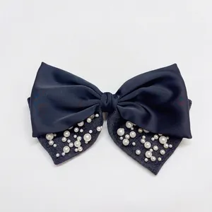 Elegante fermaglio per capelli in raso blu navy con decorazioni di perle su fondo bianco