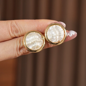 Gros plan de boucles d'oreilles cœur dorées avec incrustation à texture plissée blanche