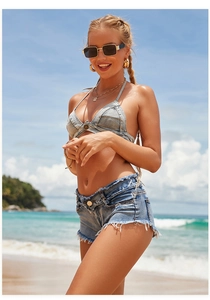 Makro-Detail von Fransenrändern und Knopftextur am hellblauen Denim-Bikini-Set