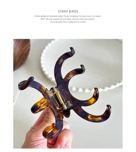 Detail showing high-quality dark tortoiseshell acetate hair claw with golden spring