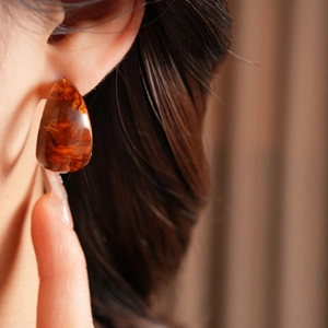 Close-up of model wearing C-shaped tortoiseshell amber resin hoop earrings