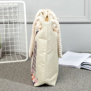 Detail view of beige canvas tote bag with thick rope handle and Eiffel Tower print