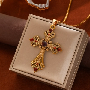 Macro-opname van een vintage gouden kruisketting met rode en champagnekleurige kristallen