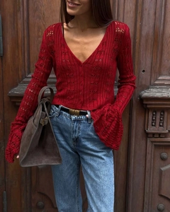 Detailed view of red hollow-out knit cardigan with V-neck and flared long sleeves
