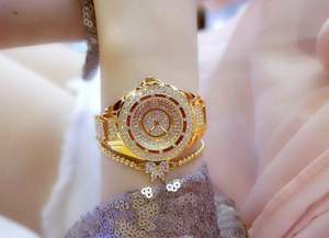 Close-up of luxury gold women's watch with crystals and matching butterfly bracelet