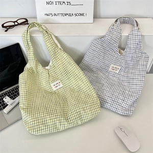 Détail de sacs fourre-tout à carreaux jaunes et gris avec étiquette sur un bureau