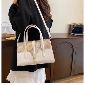 Detail of elegant lavender shoulder bag with unique textured lid and gold buckle on a model