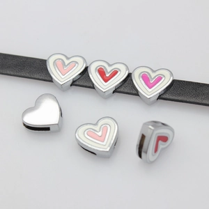 Detail of colorful enamel heart charms threaded on a black leather strap accessory