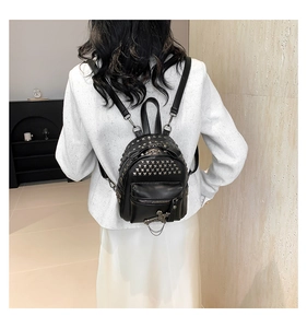 Close-up of black PU mini backpack with silver square studs and cross chain charm